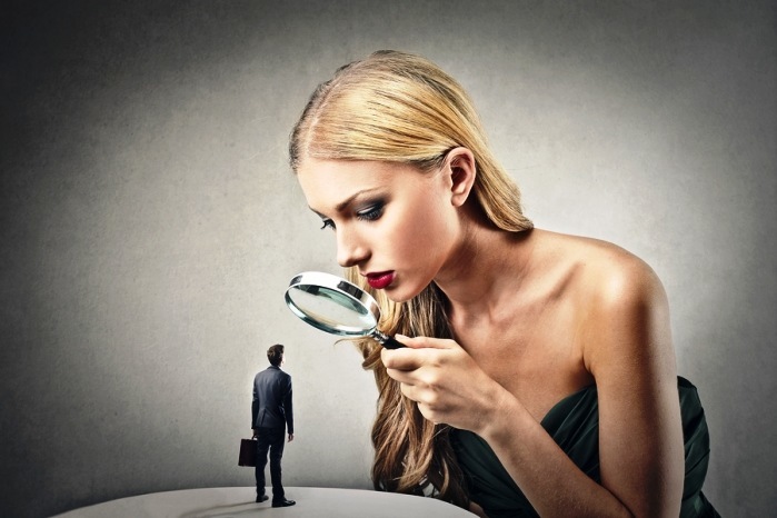 beautiful woman looking little man with magnifying glass