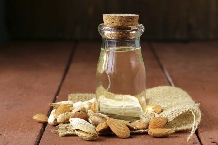 almond oil in a glass bottle with whole nuts