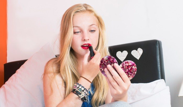 teenage girl putting on lipstick