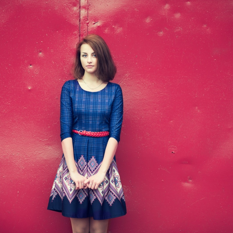 A beautiful young woman in vintage dress on a red wall