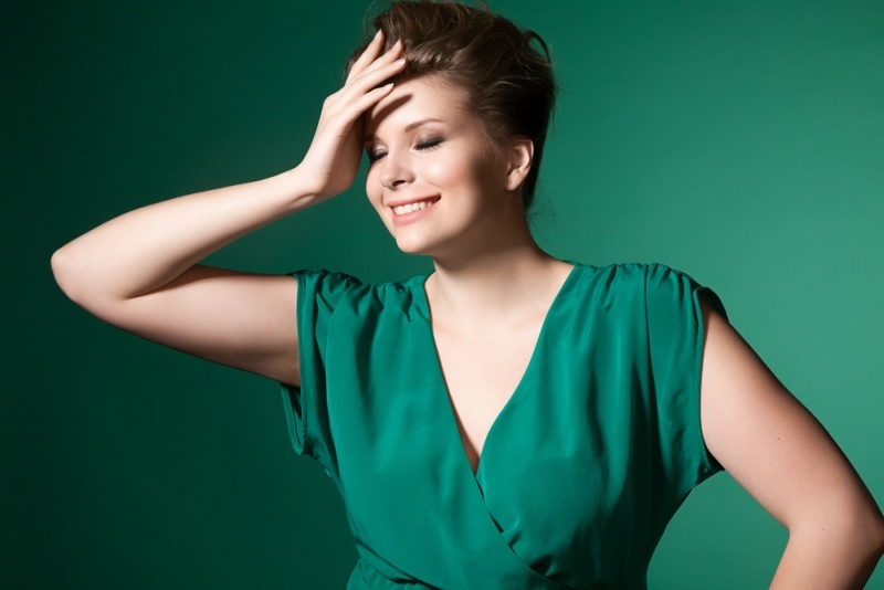 Beautiful laughing plump girl in a green evening dress and hairstyle