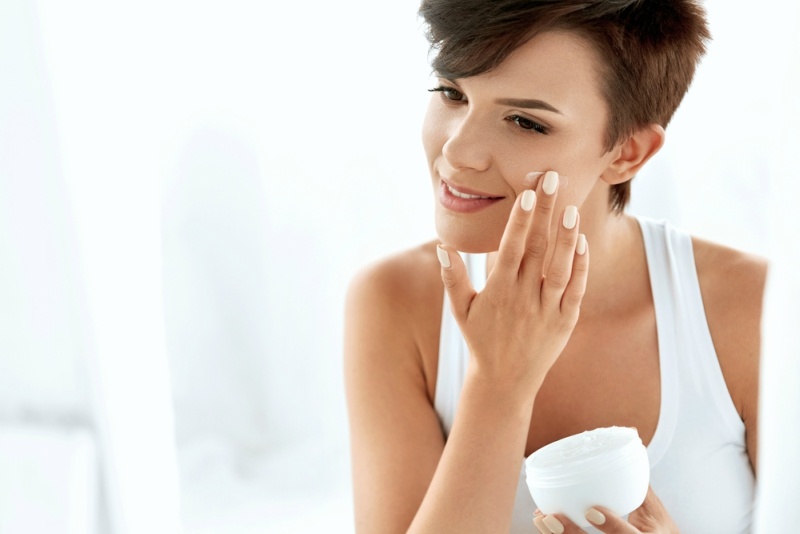 Beauty Skin Care. Beautiful Happy Woman Applying Cosmetic Cream On Clean Face.