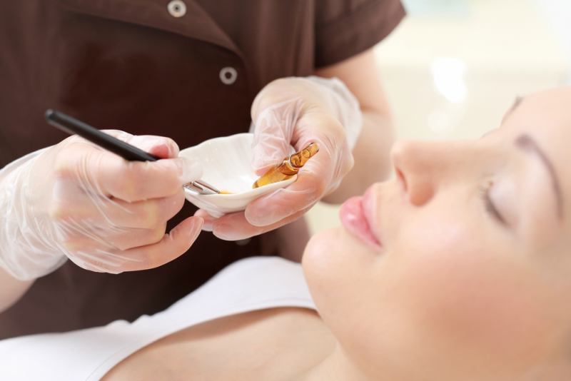 Chemical peeling, exfoliating treatment. Beautician imposes on the woman's face a cosmetic preparation.