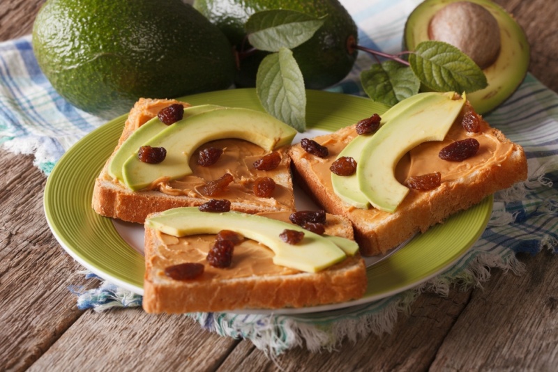 Dietary sandwich with peanut butter, avocados and raisins close-up on a plate. horizontal