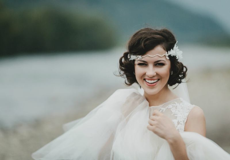 Gorgeous bride with short brunette hair smiles while posing by the river