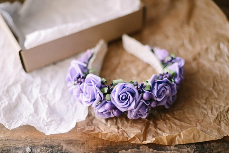 Handmade floral tiara made of flowers lie on wooden background. Fashionable hand made wreath of flowers head wear. Hand crafted fashion accessories for women