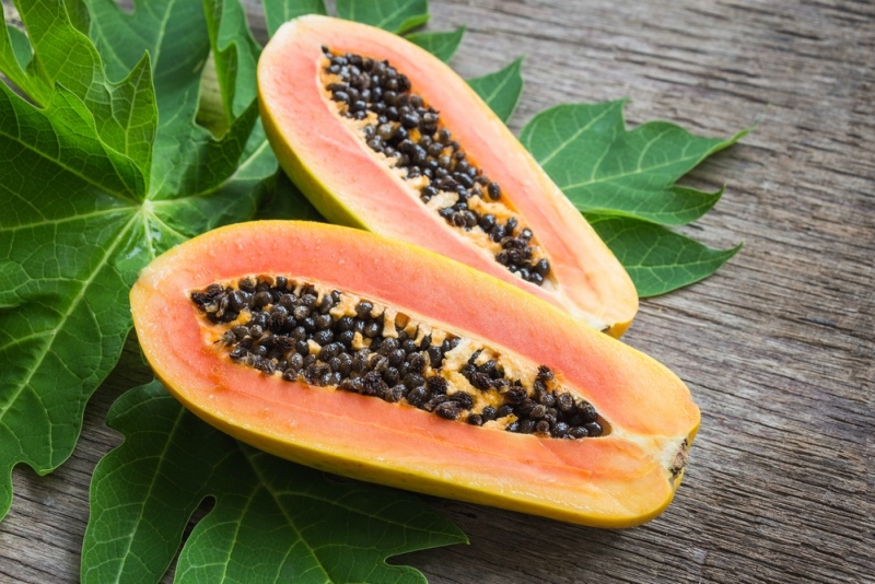 Ripe papaya with green leaf on wooden background.