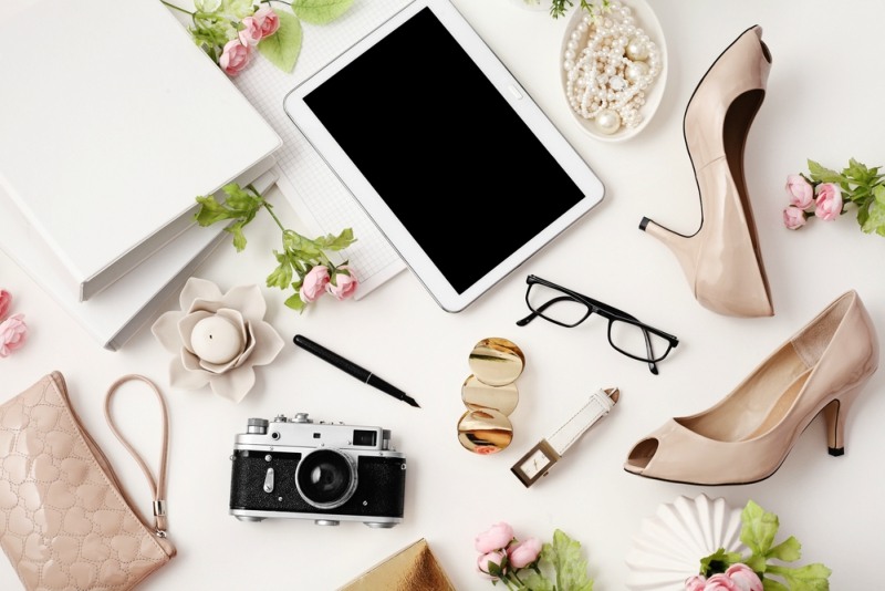 female workspace with tablet, high heels, photo camera and office supplies on white background