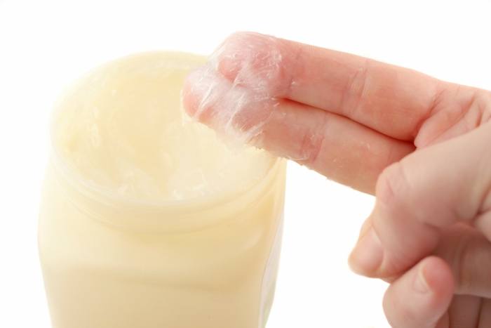 fingers dipped in jar of petroleum jelly