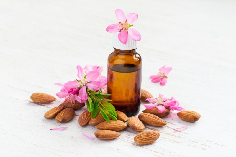 Almond oil in a small bottle, almond flowers and nuts