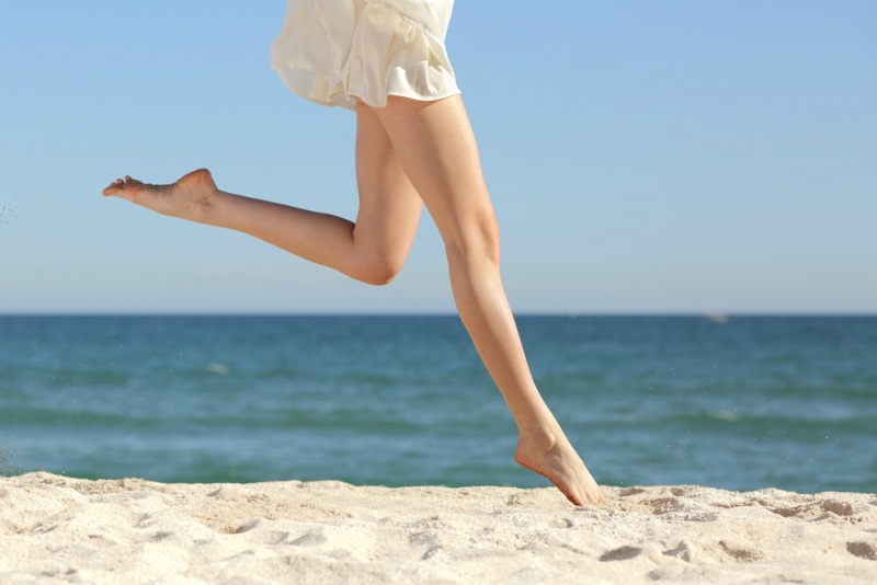 Beautiful woman long legs jumping on the beach with the sea in the background