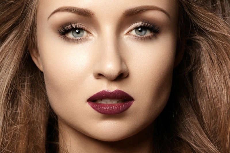 Chic evening style. Alluring woman model with luxury fashion make-up, dark red lips makeup and long hair. Trends colors, marsala wine color lipstick, strong eyebrows, sexy hair