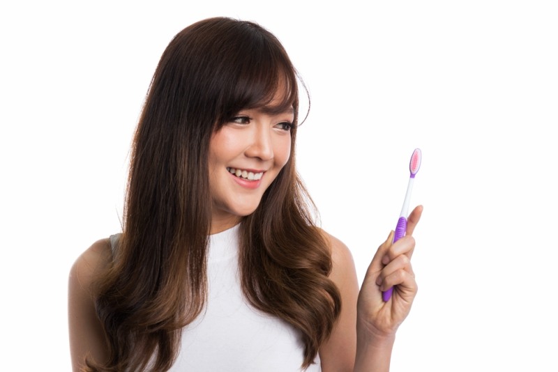 Happy young asian woman with healthy teeth holding a tooth brush