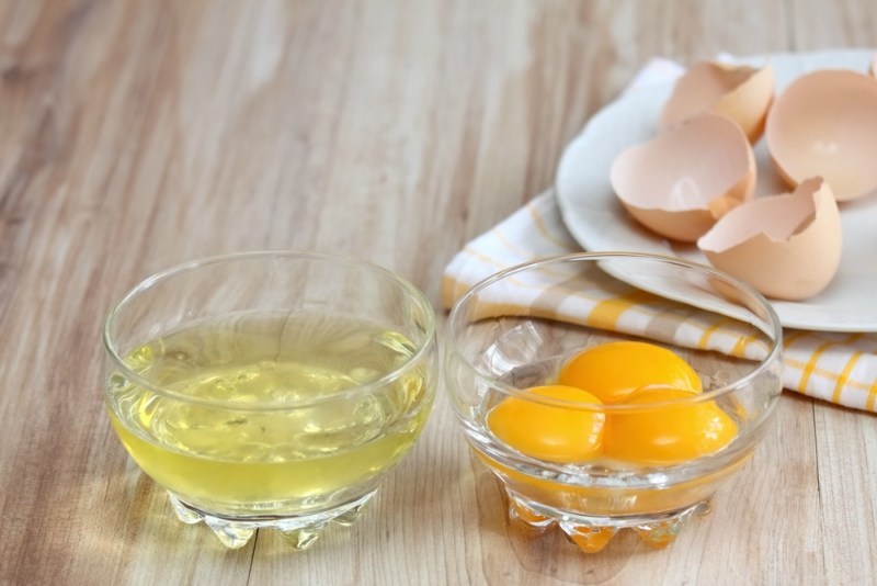 Separated egg white and yolks into two bowls and broken egg shells are at background