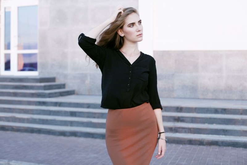 Stylish fashion portrait of trendy casual model in black shiffon blouse, brown pencil skirt