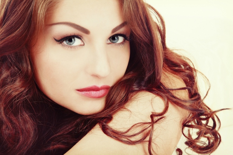 Vintage style portrait of young beautiful woman with eyebrows tattoo and long curly hair