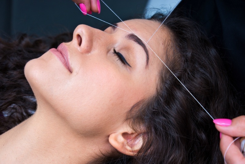 attractive woman in beauty salon on facial hair removal threading procedure