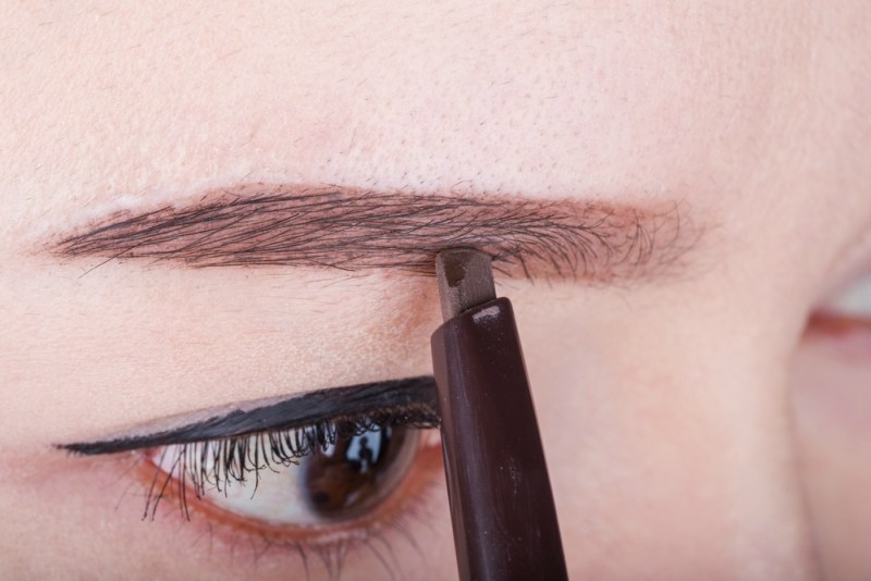 close-up woman using pencil makeup eyebrow