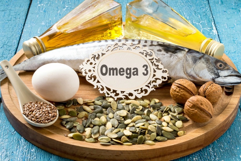 source fatty acids Omega 3 (mackerel, camelina oil, rapeseed oil, organic egg, pumpkin and flax seeds, walnuts) on a round wooden board