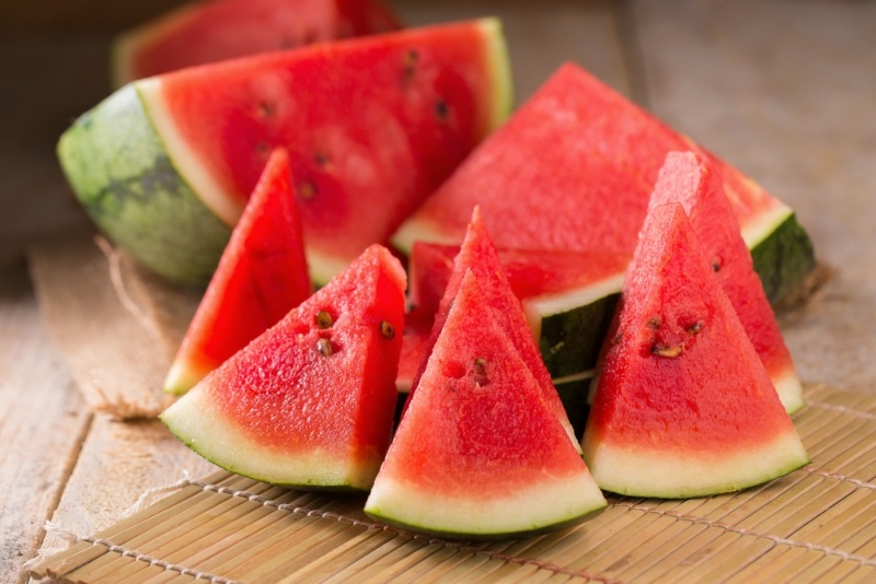 watermelon and watermelon pieces in a wooden background.