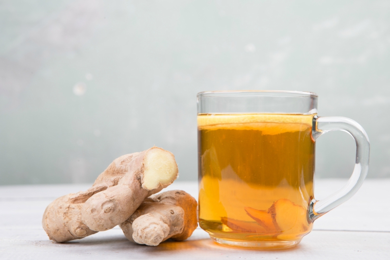 Ginger tea in a cup on wooden background
