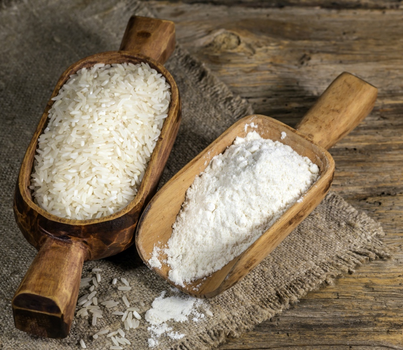 Rice and rice flour in old wooden bowl