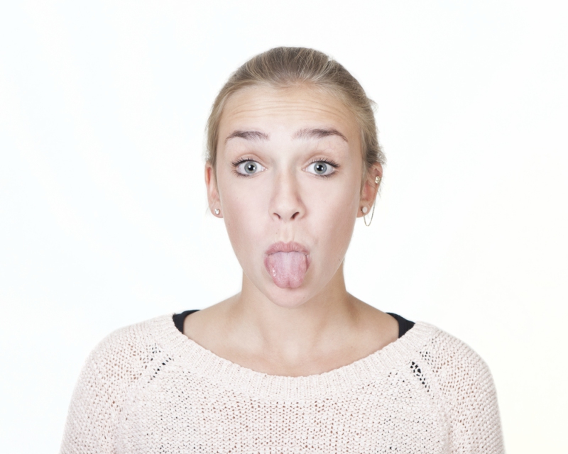 young woman with blond hair and blue eyes stretched out her tongue, portrait